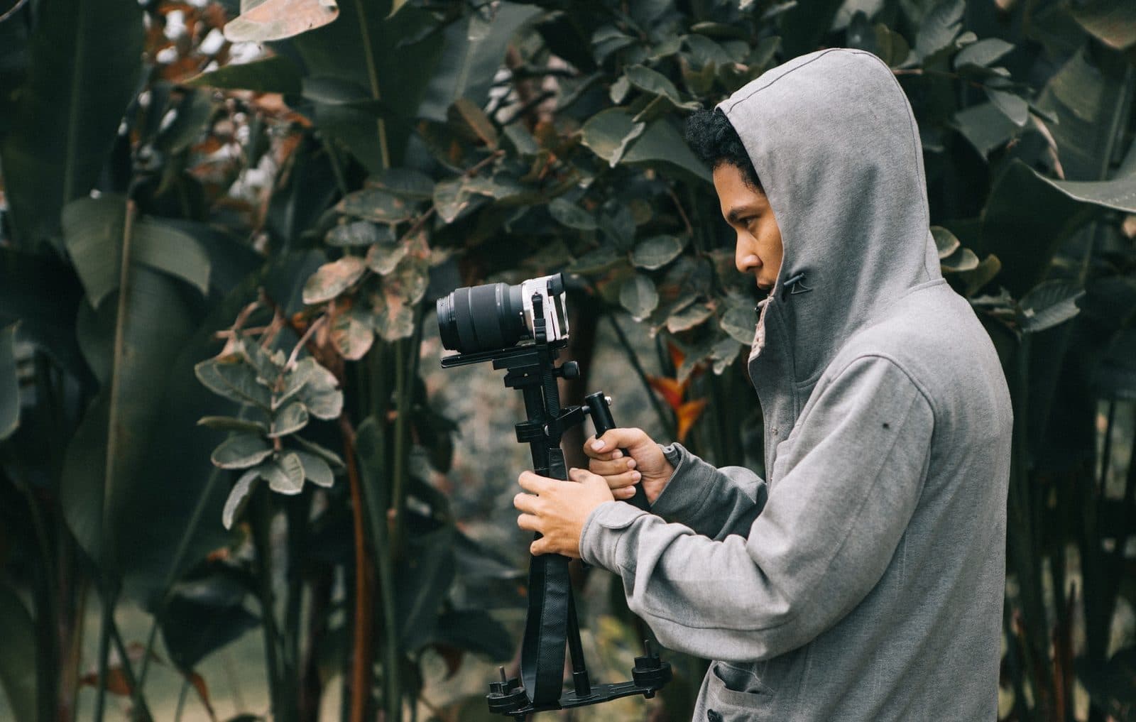 A photographer steadying a camera on a handheld gimbal rig outdoors