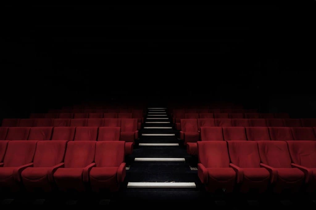 Empty rows of red seats in a darkened cinema