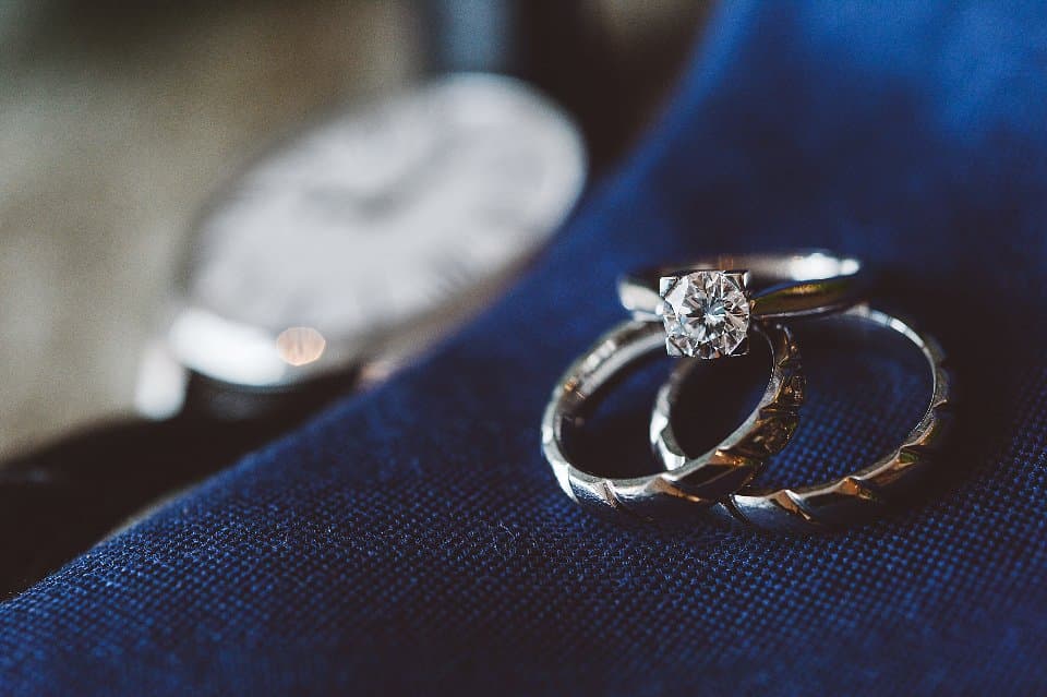 Three wedding and engagement rings resting on blue fabric